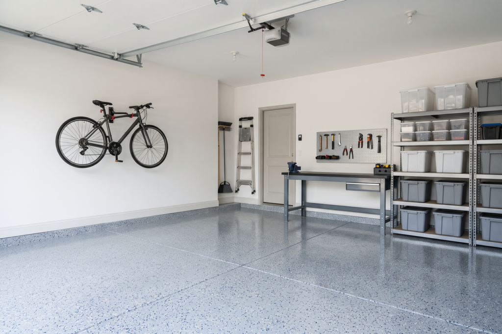 Tidy garage with a light gray and blue flake floor, a wall-mounted bike rack, a gray workbench and plain storage bins on open shelves