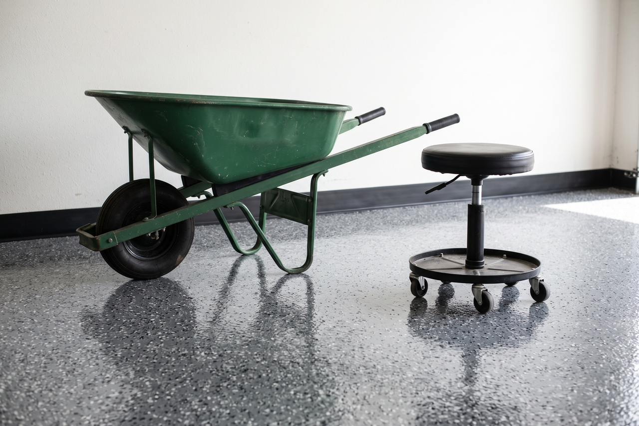 Wheelbarrow and a rolling shop stool resting on a glossy gray flake coated garage floor